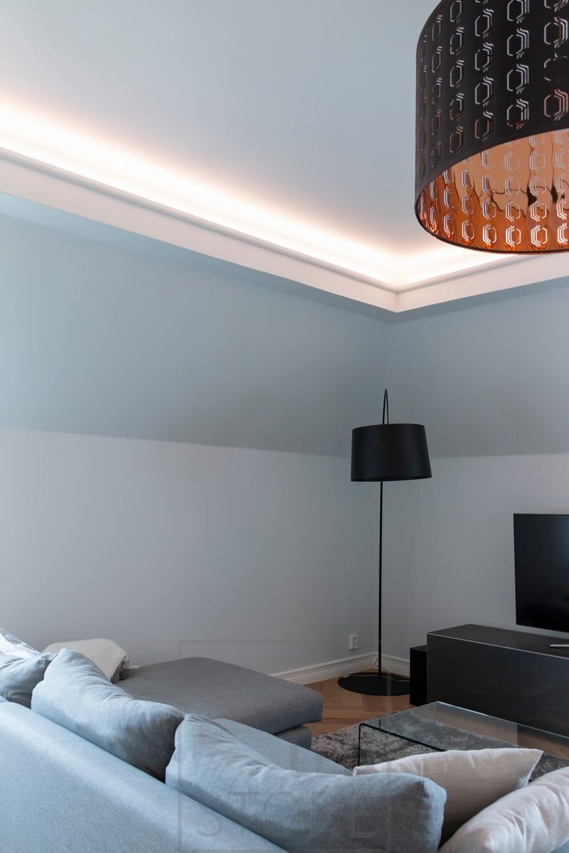 In the living room, indirect lighting directed to the ceiling. The lighting is atmospheric and soft, without glare.